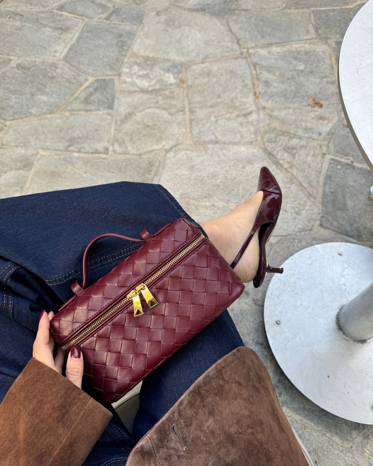 A sophisticated burgundy red woven handbag crafted from high-quality vegan leather, featuring a structured silhouette, gold lock detail, and a detachable adjustable strap for versatile crossbody, shoulder, or handheld wear.