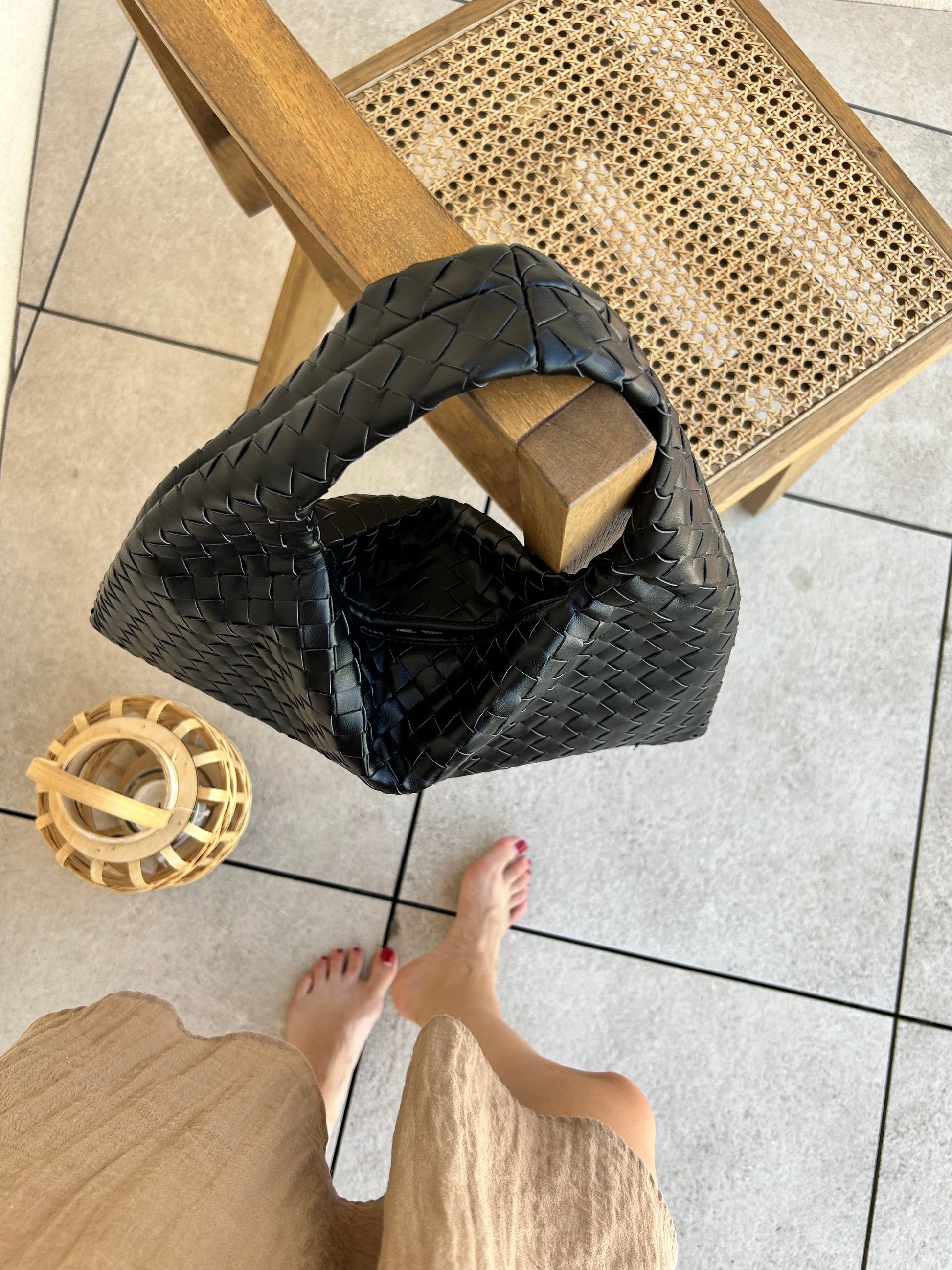 Black woven tote bag placed on chair with modern minimalist aesthetic