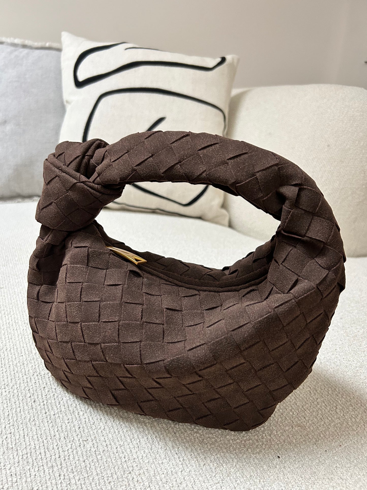 Braune Teddy-Clutch aus weichem veganem Wildleder, in der Hand getragen.