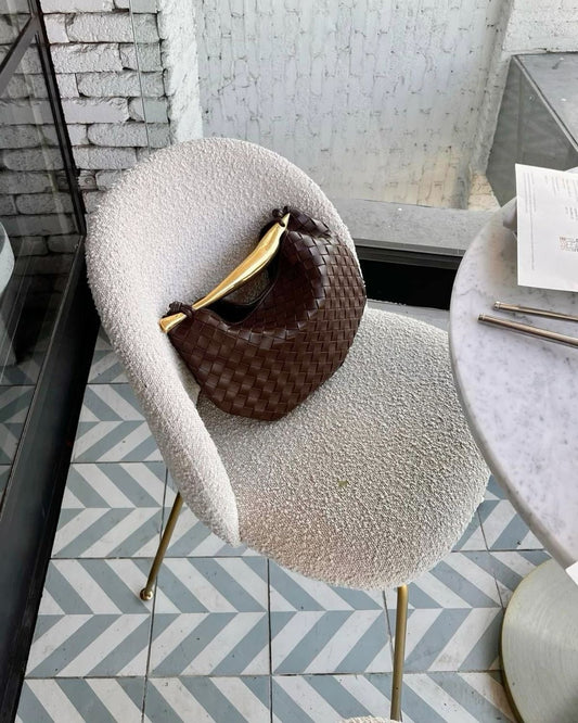 Brown woven clutch bag on modern chair minimalist interior styling