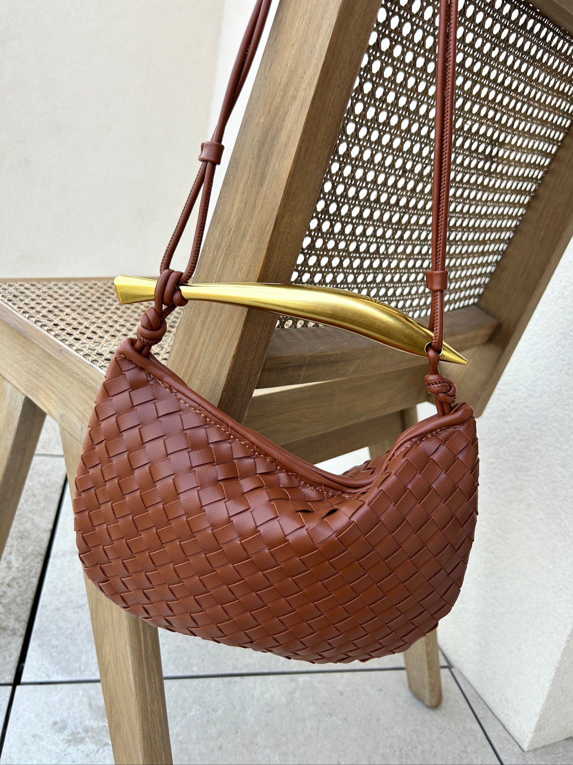 Brown woven crossbody bag crafted from premium vegan leather with an elegant gold-tone handle and adjustable strap.