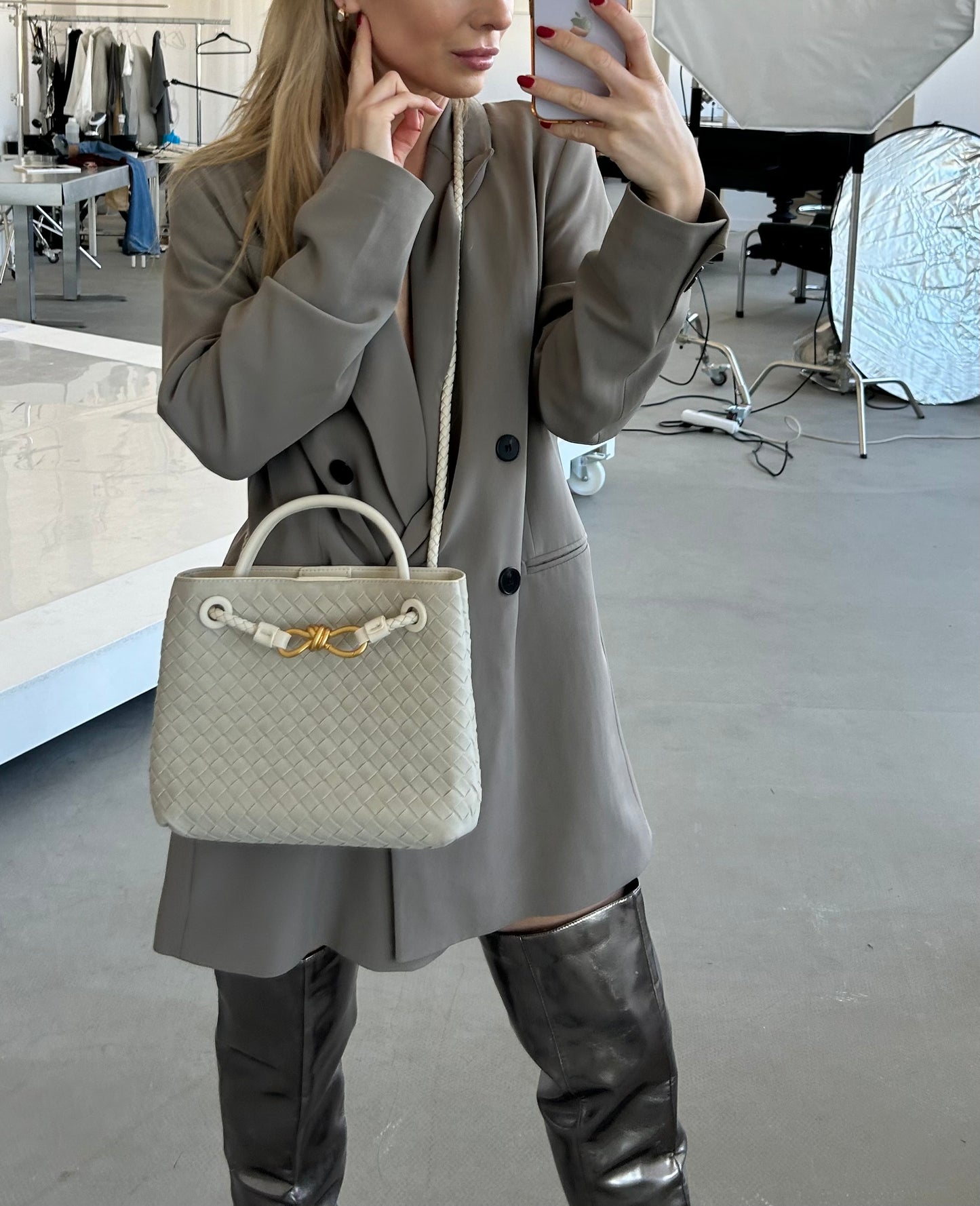 This trendy woven bag in light colour is made from vegan suede, arranged stylishly on boucle sofa with fashion magazine to create luxury aesthetic. wonderful birthday gift for a fashion-forward friend. Designer inspired boxy handbag in woven style