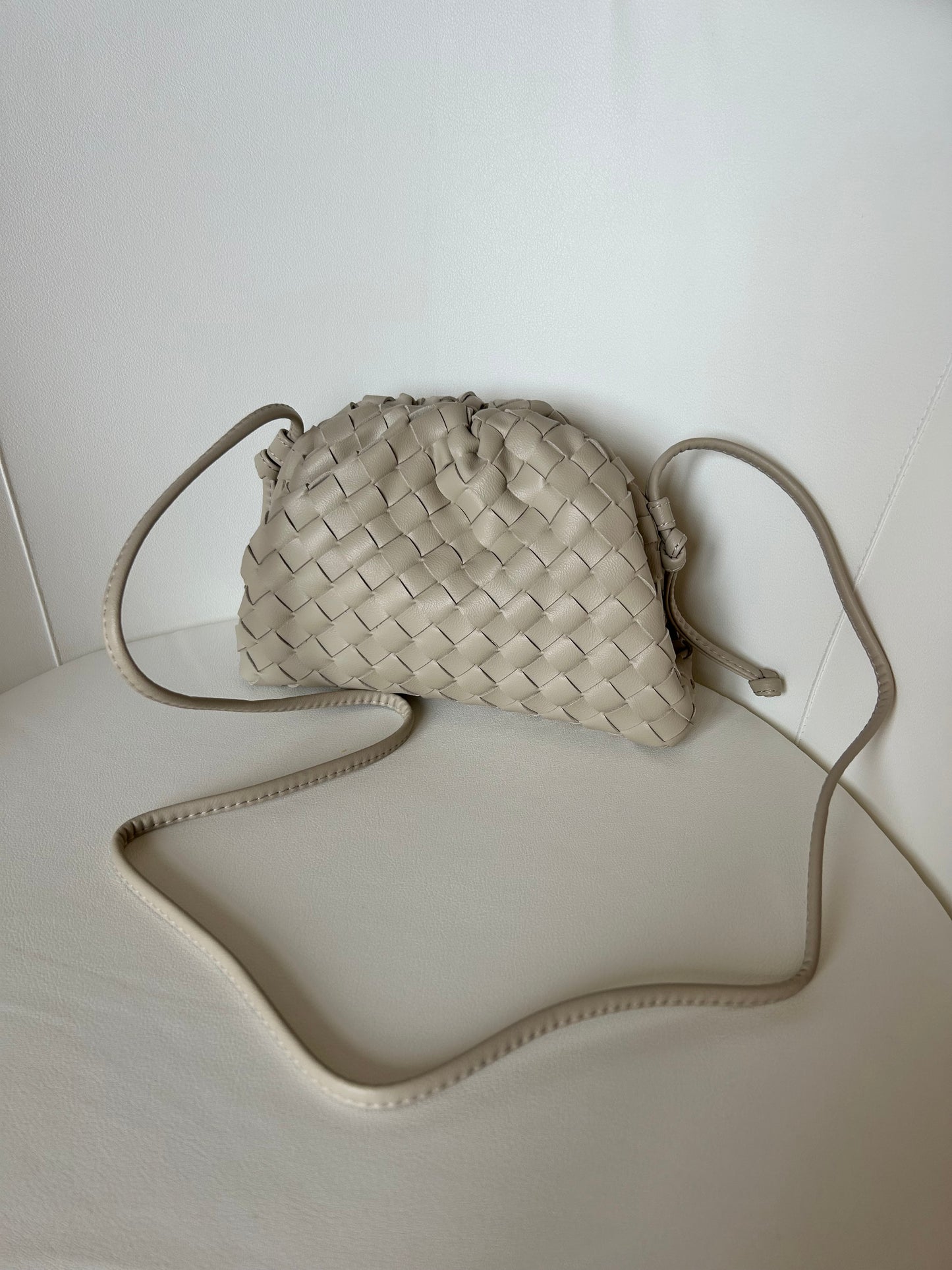 Designer-inspired beige crossbody bag with woven texture, adjustable strap and timeless minimalist silhouette.