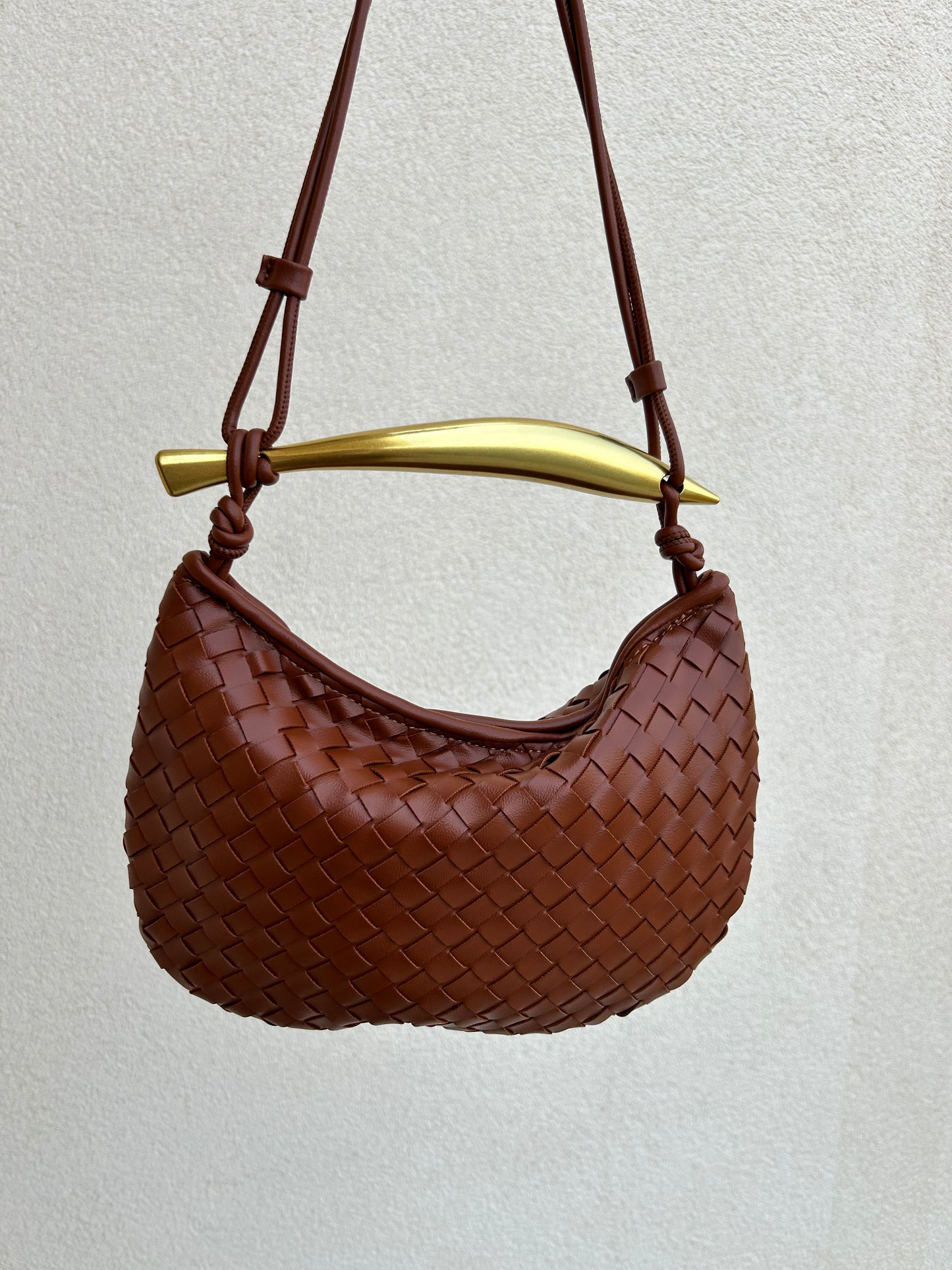 Designer-inspired woven brown handbag with adjustable shoulder strap and premium gold hardware.