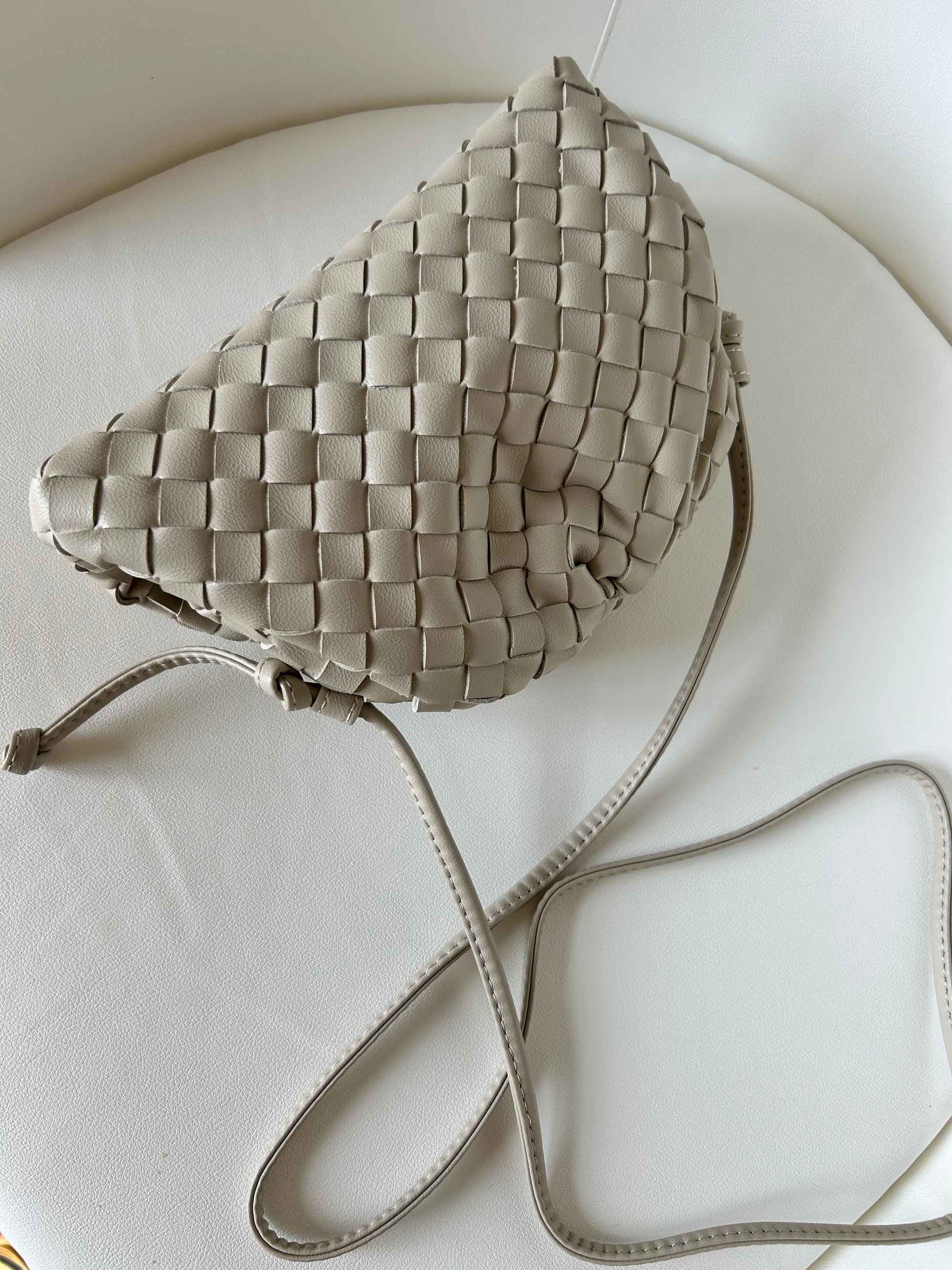 Elegant vegan leather crossbody bag in beige with luxury-inspired woven detailing.