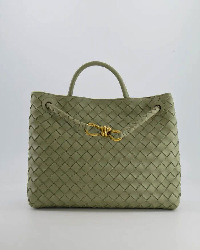 Green designer inspired woven handbag with a gold clasp on a white background