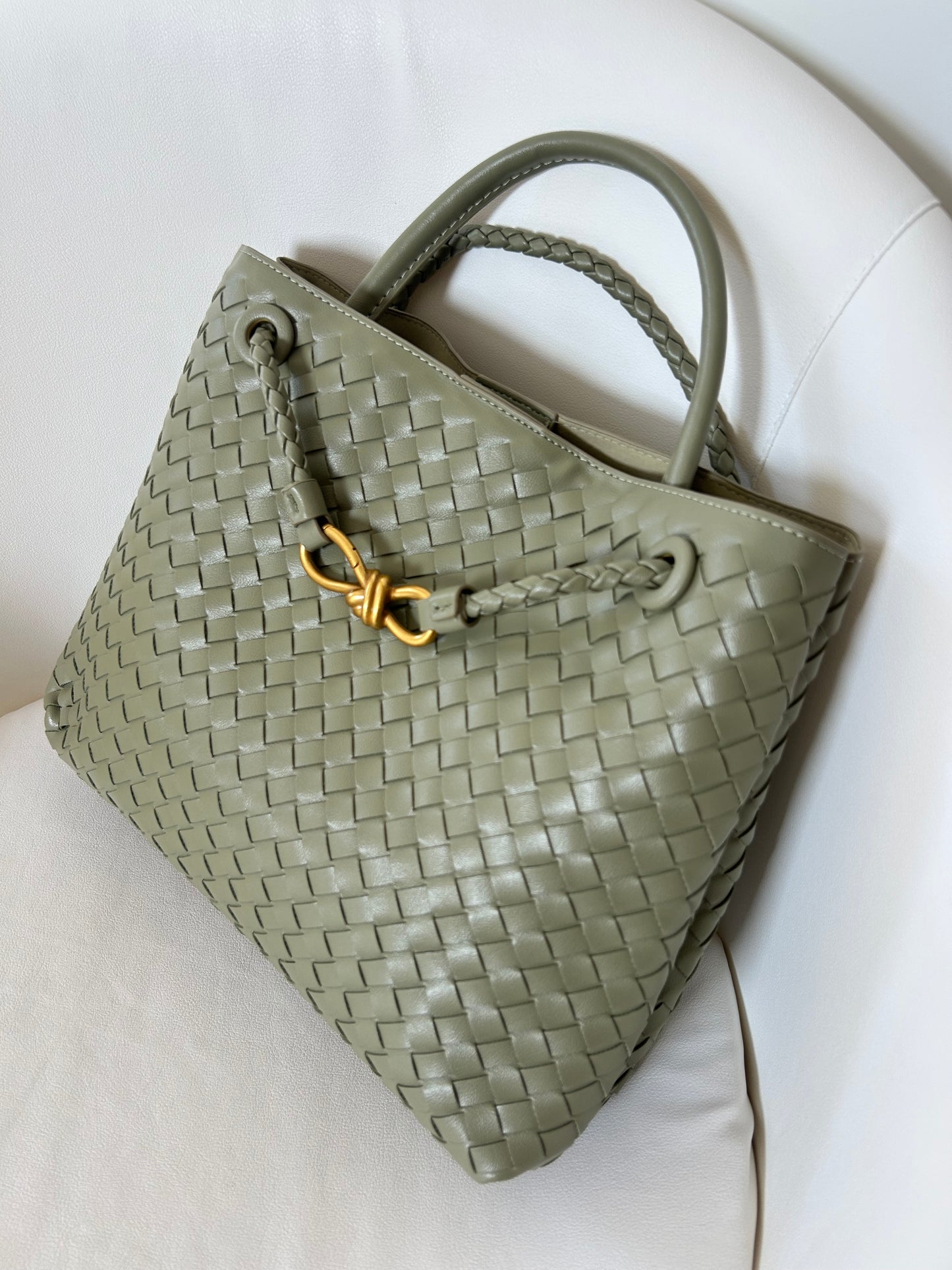 Green woven handbag with a gold clasp on a white background
