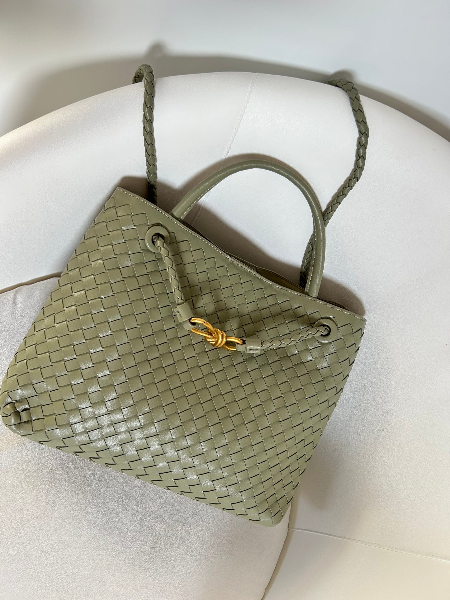 Green woven handbag with a gold clasp on a white surface. designer inspired crossbody handbag for everyday wear