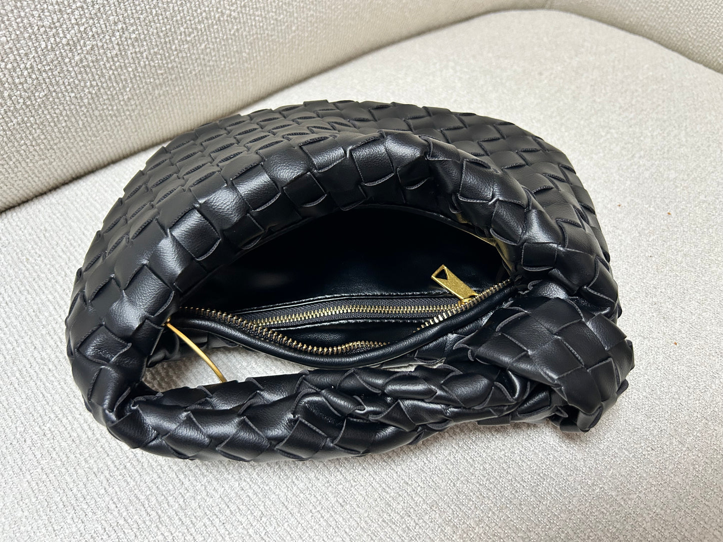 Interior of black woven clutch bag with essentials