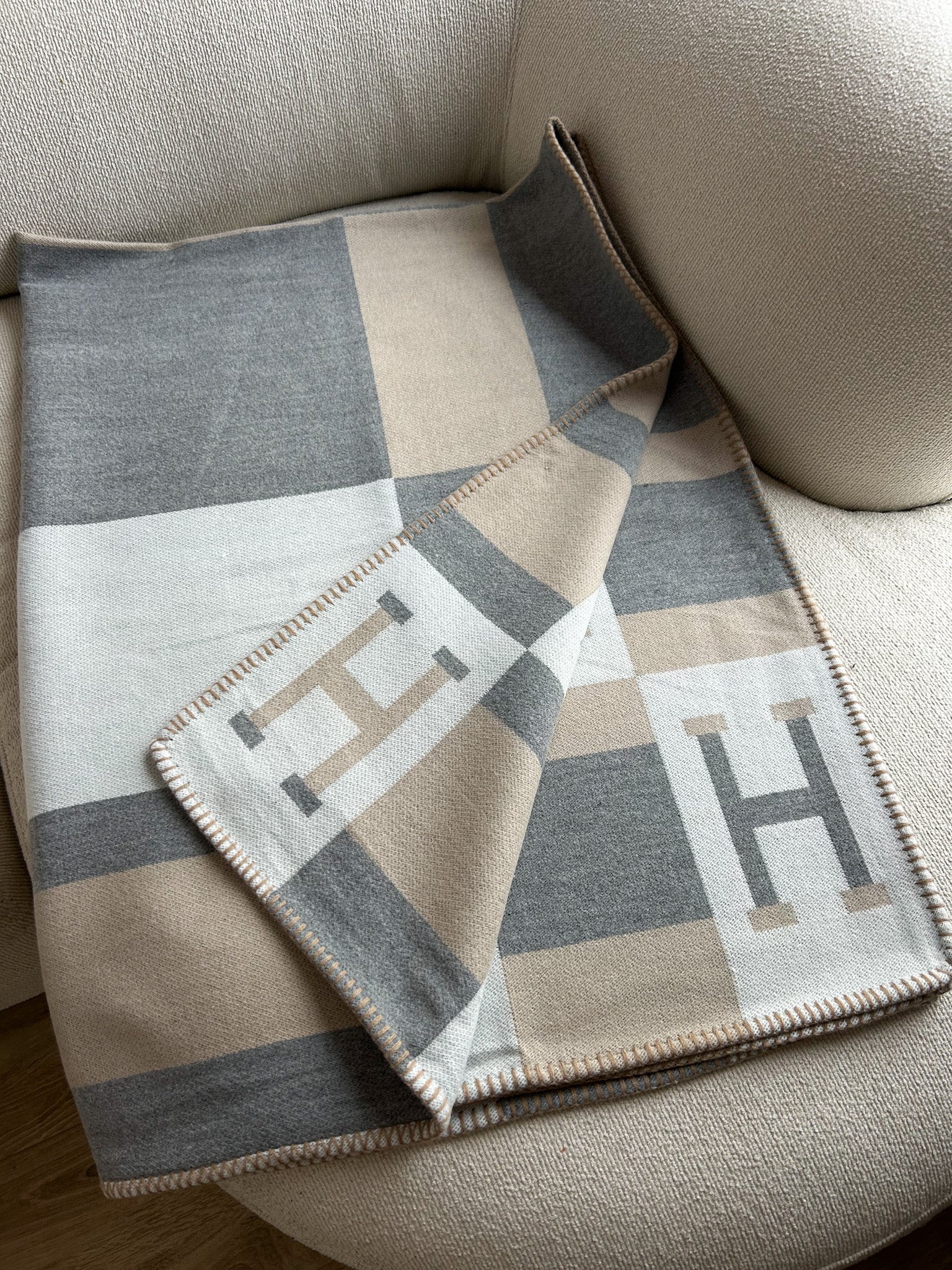 Luxury Scandinavian throw blanket in neutral beige and grey tones draped over modern chair