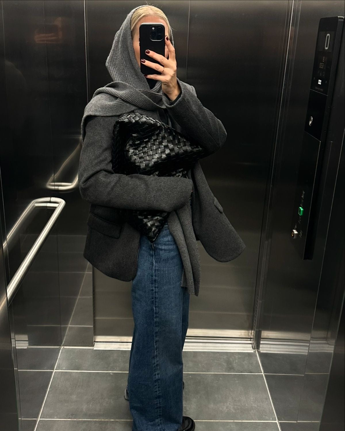Minimalist black woven tote bag styled with white outfit in elevator