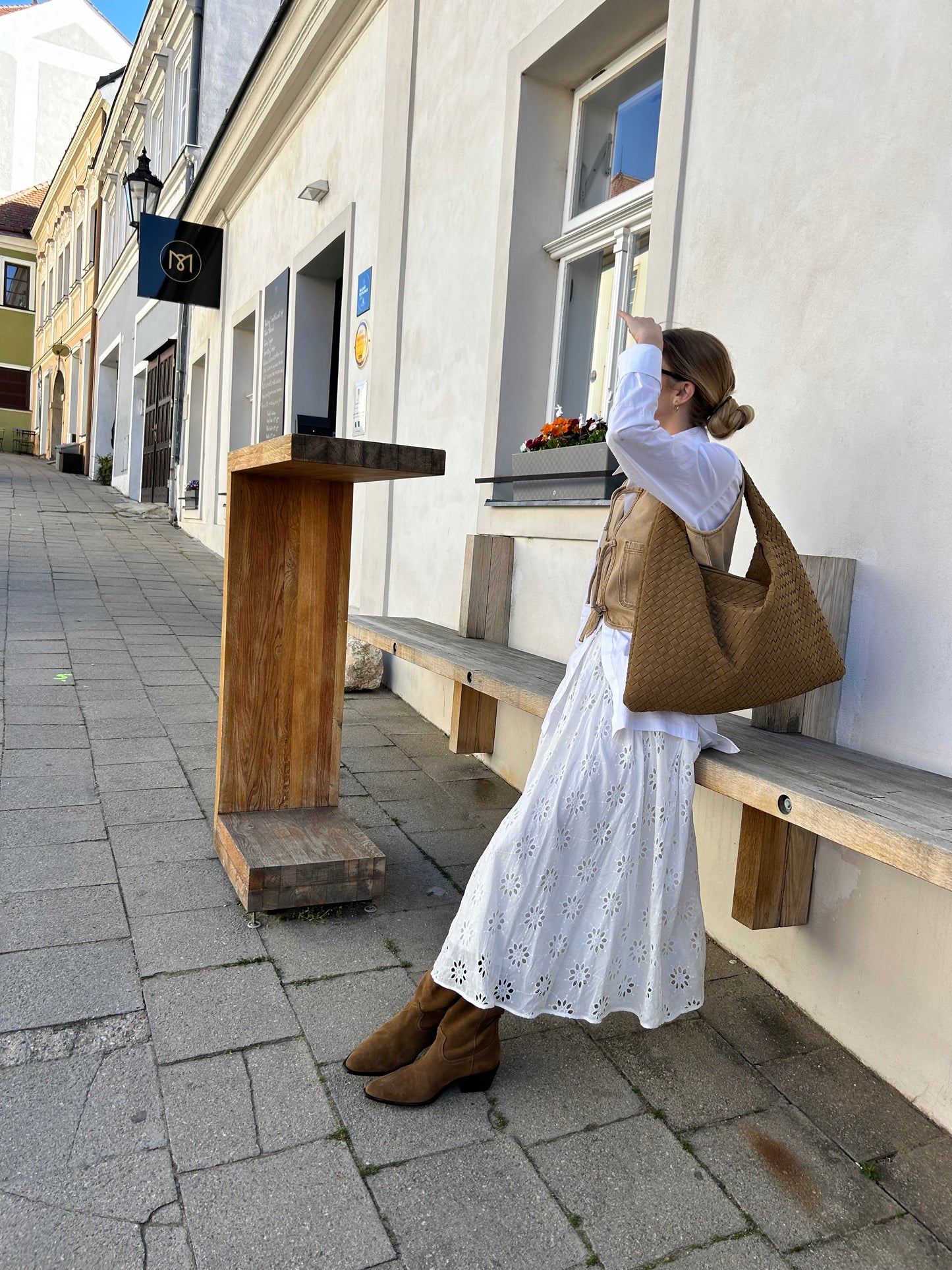 Minimalist caramel woven vegan suede handbag styled with white outfit and brown suede cowboy boots