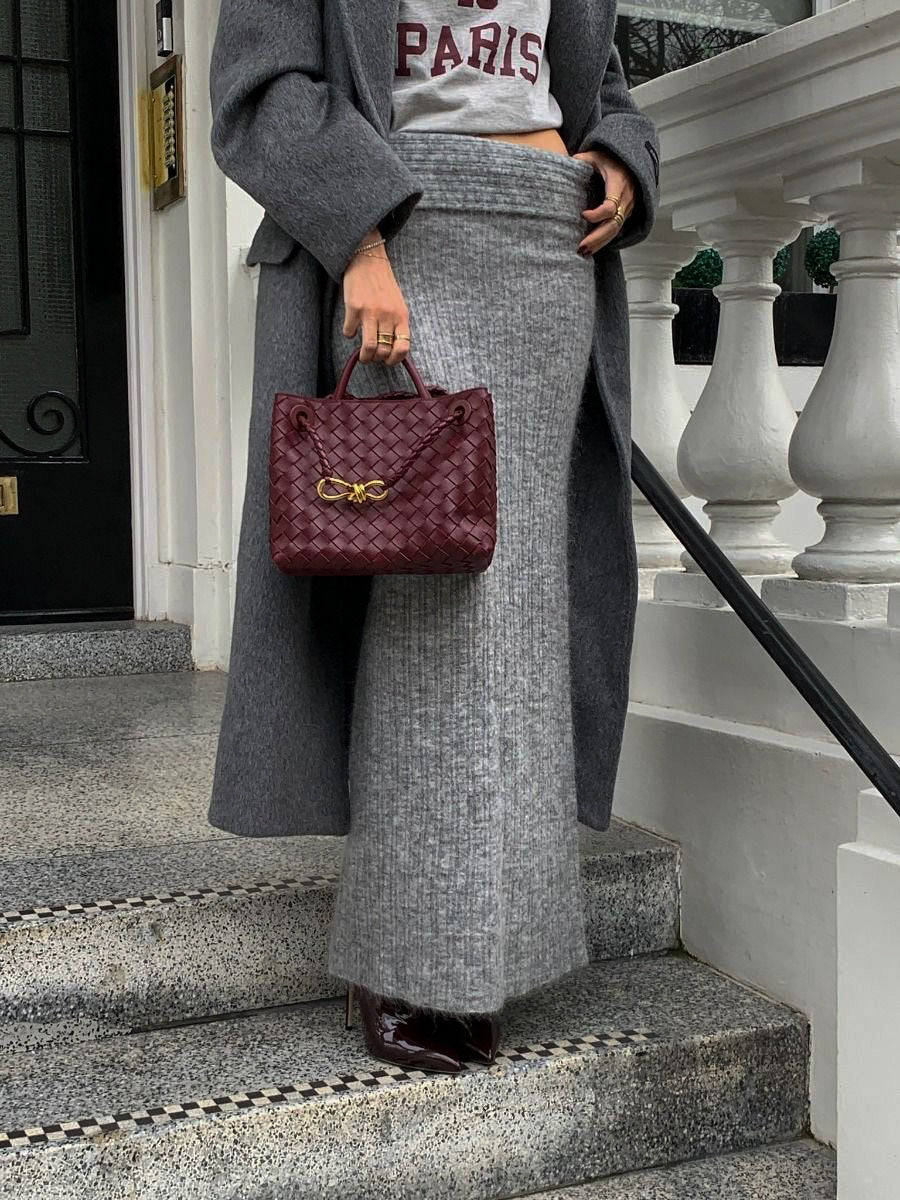 PattyB burgundy woven purse featuring gold knot accent, paired with grey knitwear and coat — affordable luxury handbag.