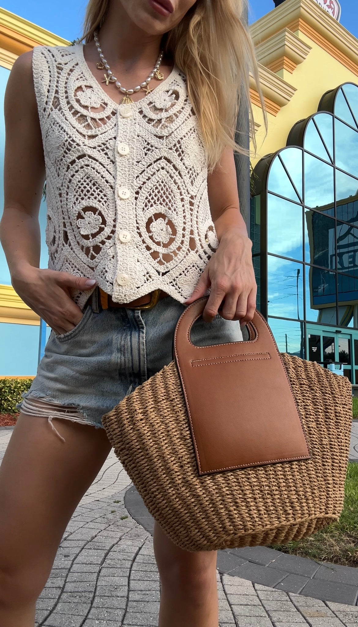 Person holding a woven beach bag with a building in the background in Florida, Cocoa Beach