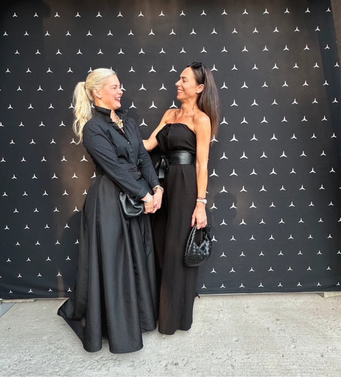 Red carpet event where 2 women are congratulating each other. One of them is wearing a black woven knot bag for women in black colour. This bag is made from highest quality vegan leather