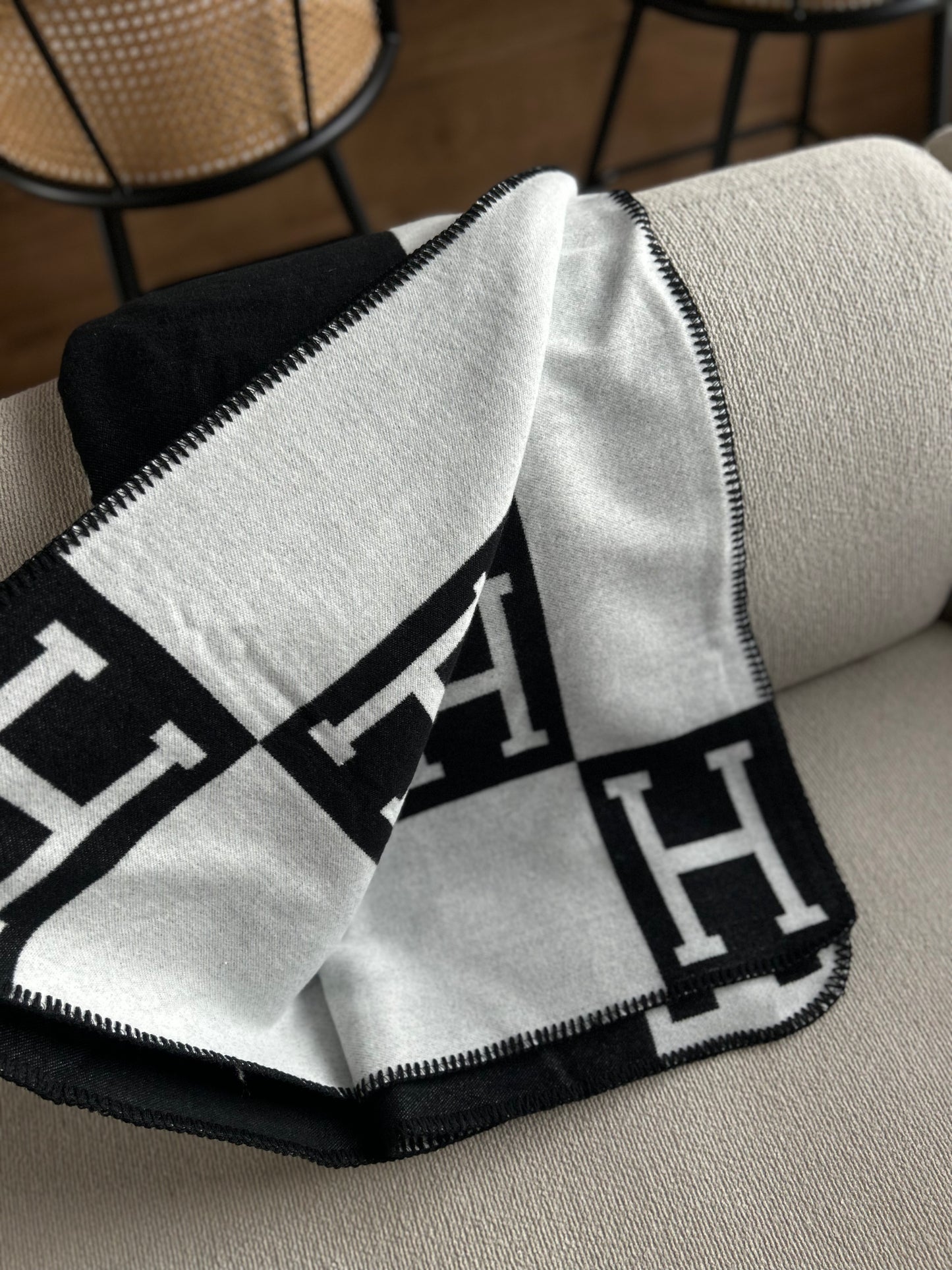 Black and white patterned blanket draped over a chair with a blurred background. Soft knit black and white blanket folded on chair minimalist interior styling