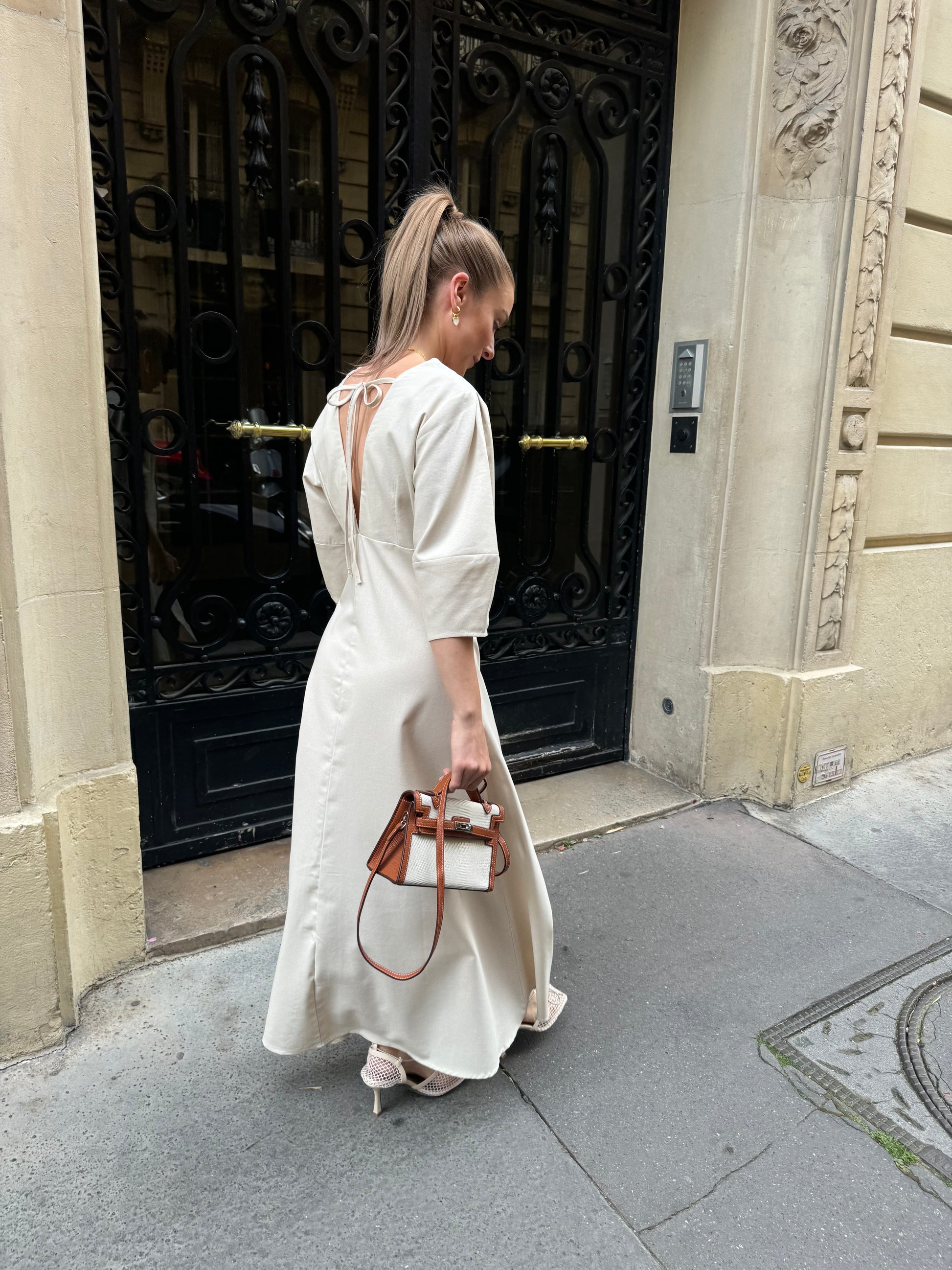 Woman in a white dress standing in front of a decorative door entrance.
