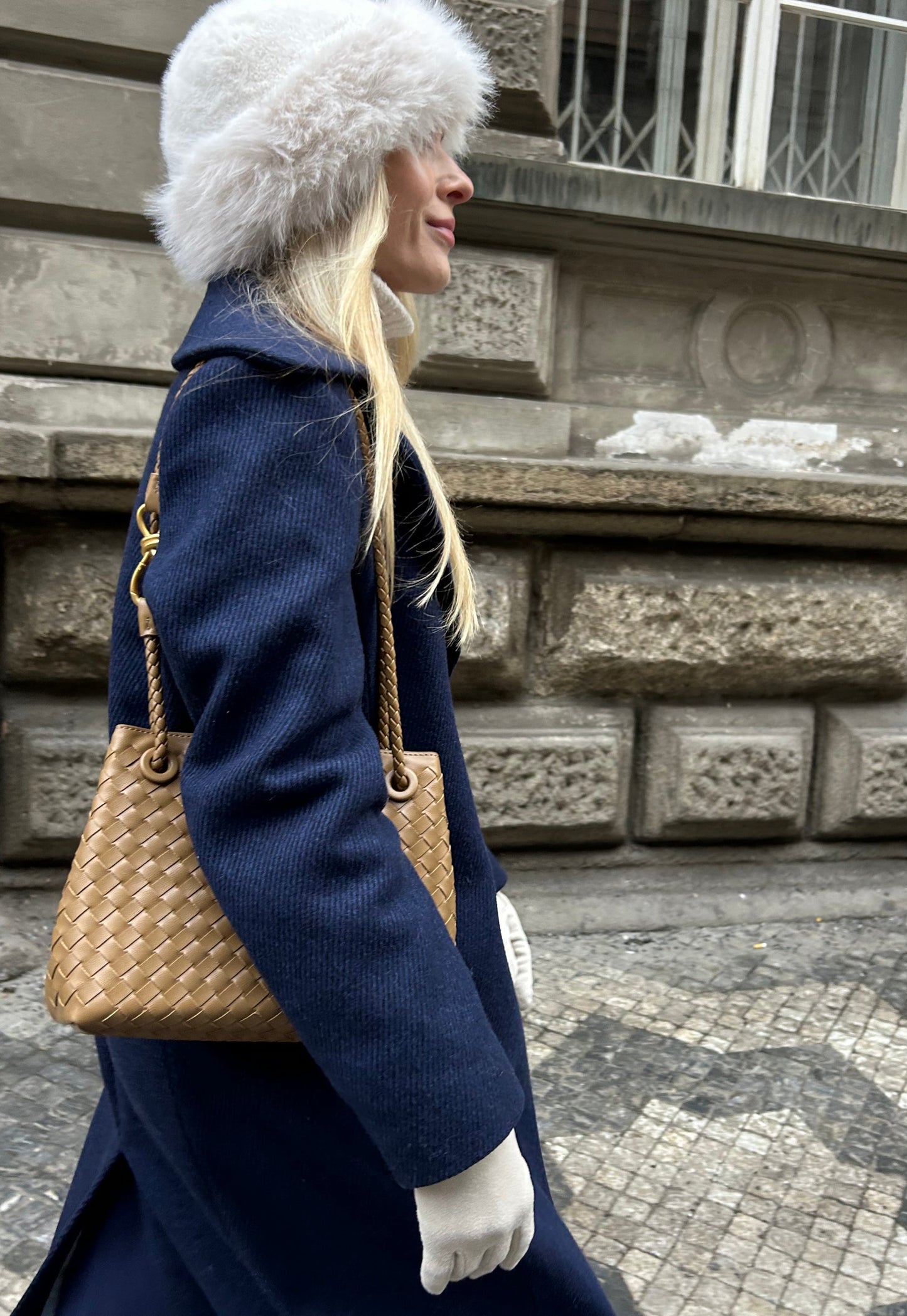 Woman wearing a woven mini vegan leather handbag as a crossbody while walking in the city of Prague