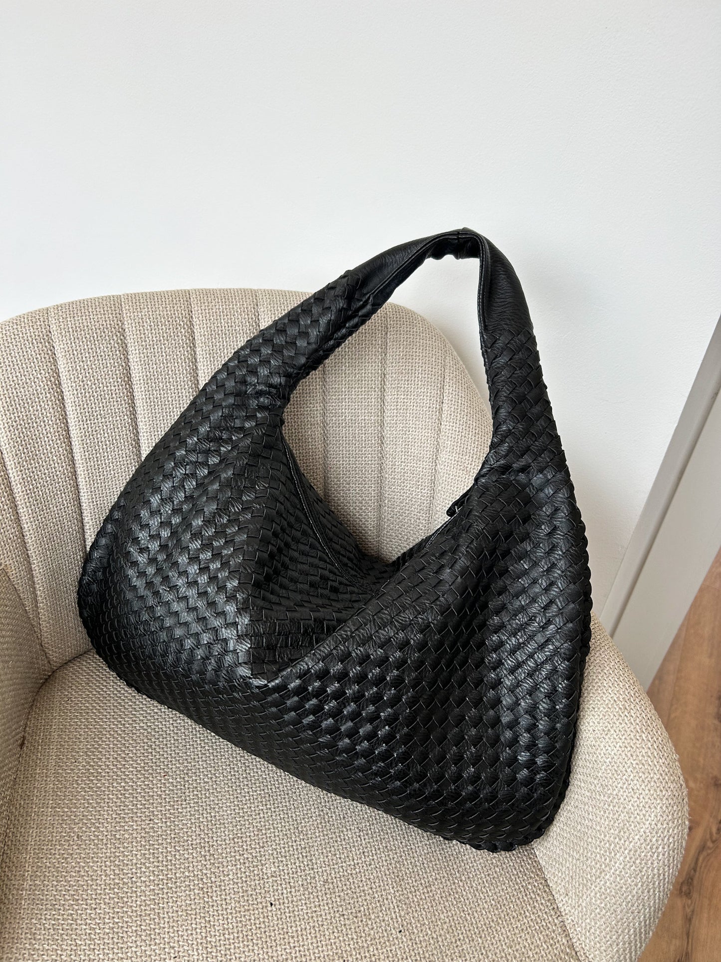 Large black woven vegan leather shoulder bag with a soft knotted handle and triangle zip, designed for work or everyday use. A popular minimalist style from a Czech brand.
spacious women’s handbag, modern everyday work bag, cruelty-free large shoulder bag