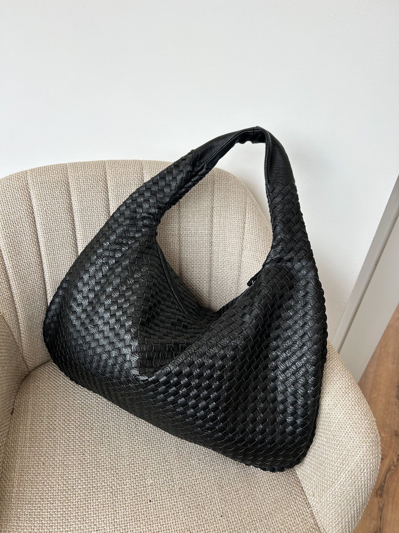 Large black woven vegan leather shoulder bag with a soft knotted handle and triangle zip, designed for work or everyday use. A popular minimalist style from a Czech brand.
spacious women’s handbag, modern everyday work bag, cruelty-free large shoulder bag