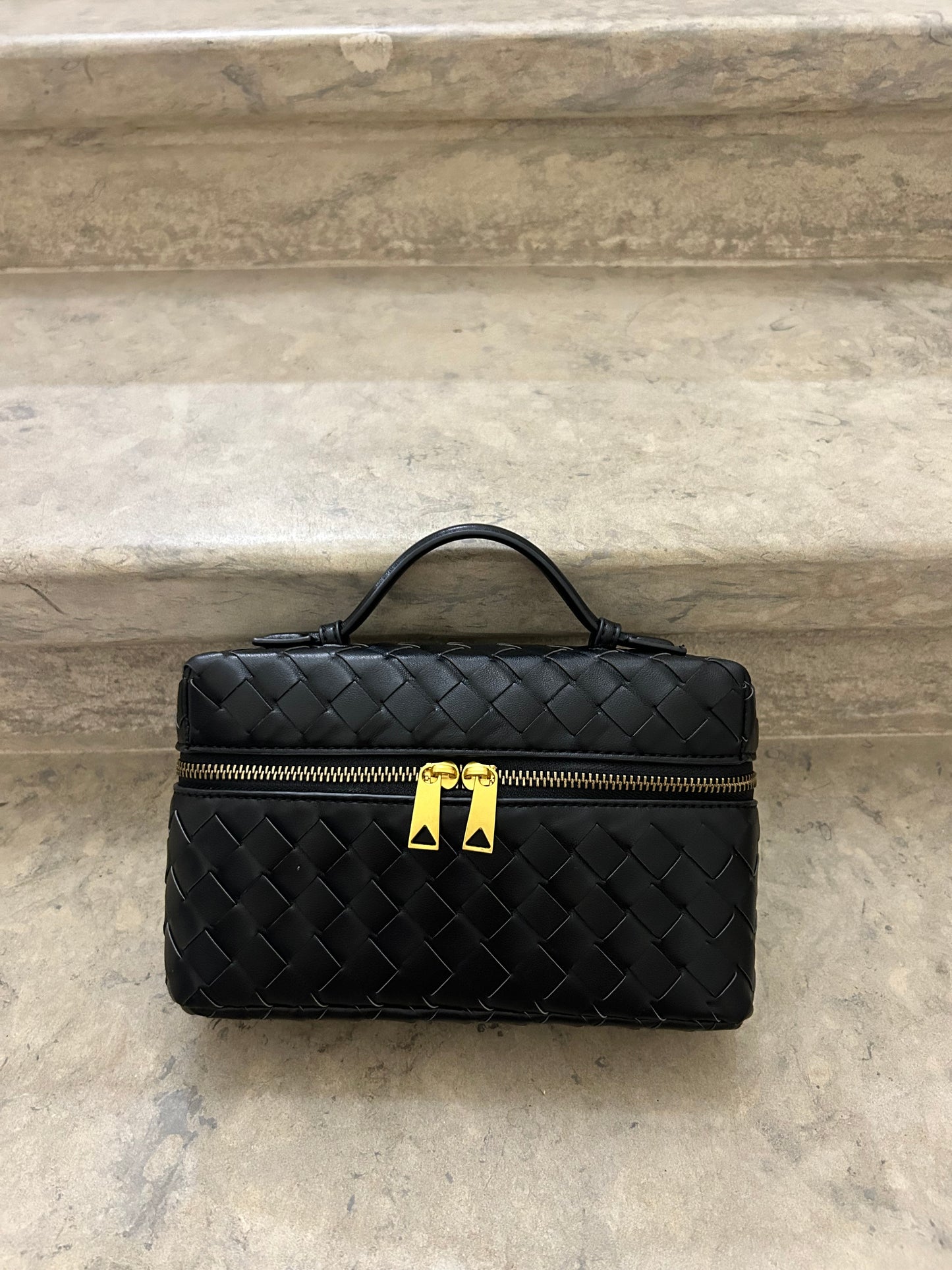beautiful woven black box bag which can be worn as a Shoulder Hobo Bag.braided top handle clutch placed on stairs with black boots detail to create minimalist aesthetic shot.Fashion influencer with her bag made from vegan leather inspired by designer