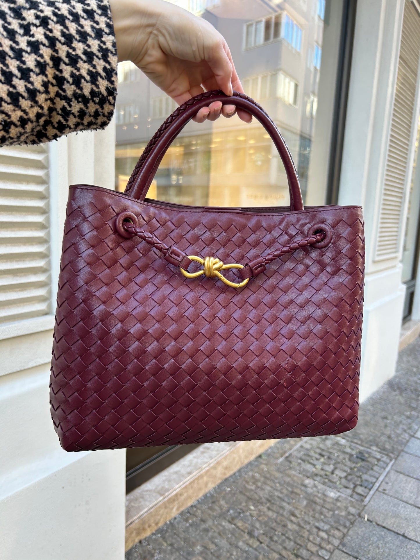 luxury handbag in braided style held in hand by the handle. Hand woven shoulder bag for women can also be worn as a crossbody bag - ideal for everyday wear like work or travel. Practical inside compartments to fit all your essentials and gold detail.