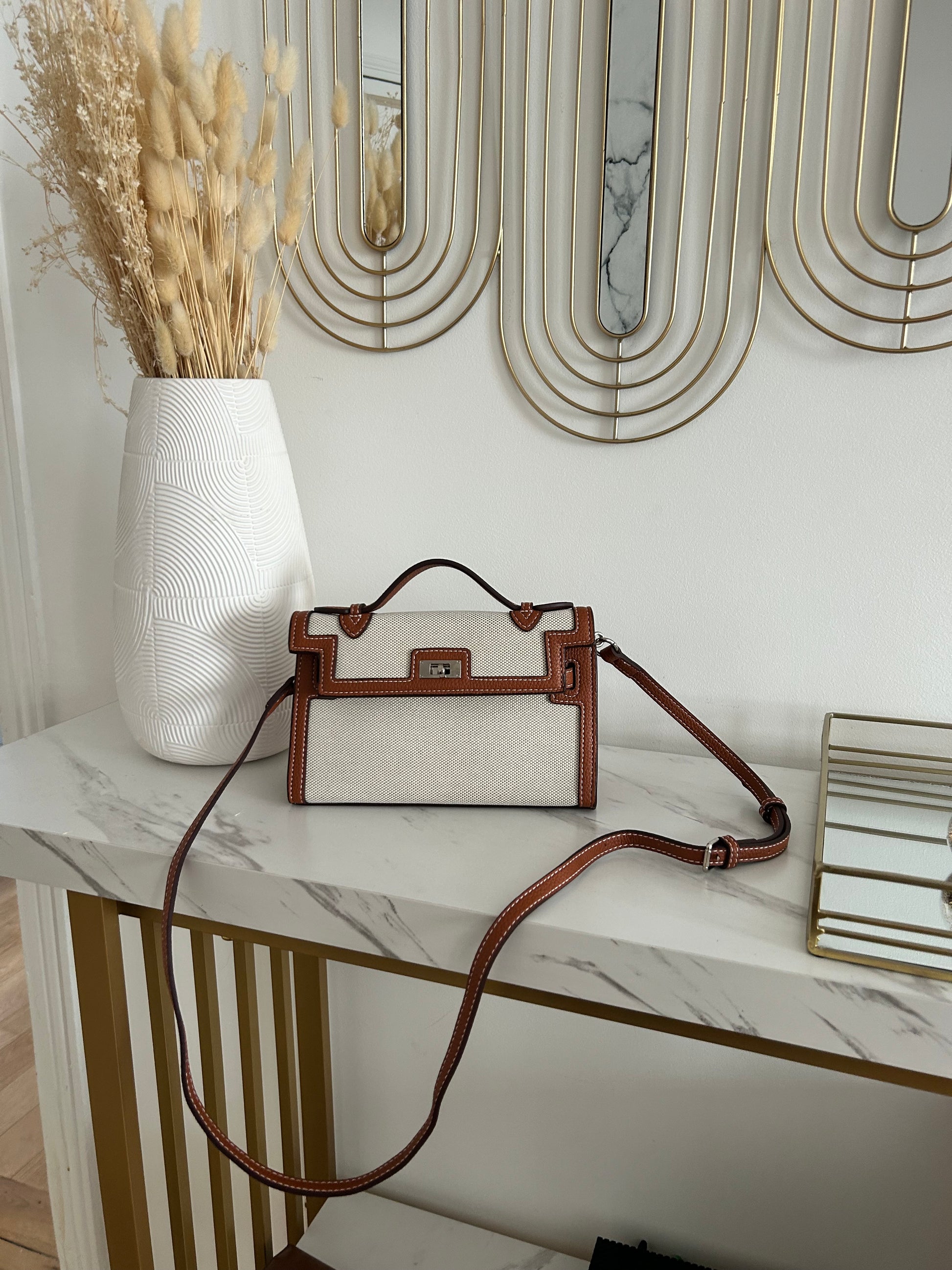 Durable, luxe-quality canvas with leather-look accents
Bold monochrome colorway for versatile, timeless style
Eye-catching belt buckle-inspired front detail
Top handle for elevated elegance + detachable strap ready for boss-on-the-go moments