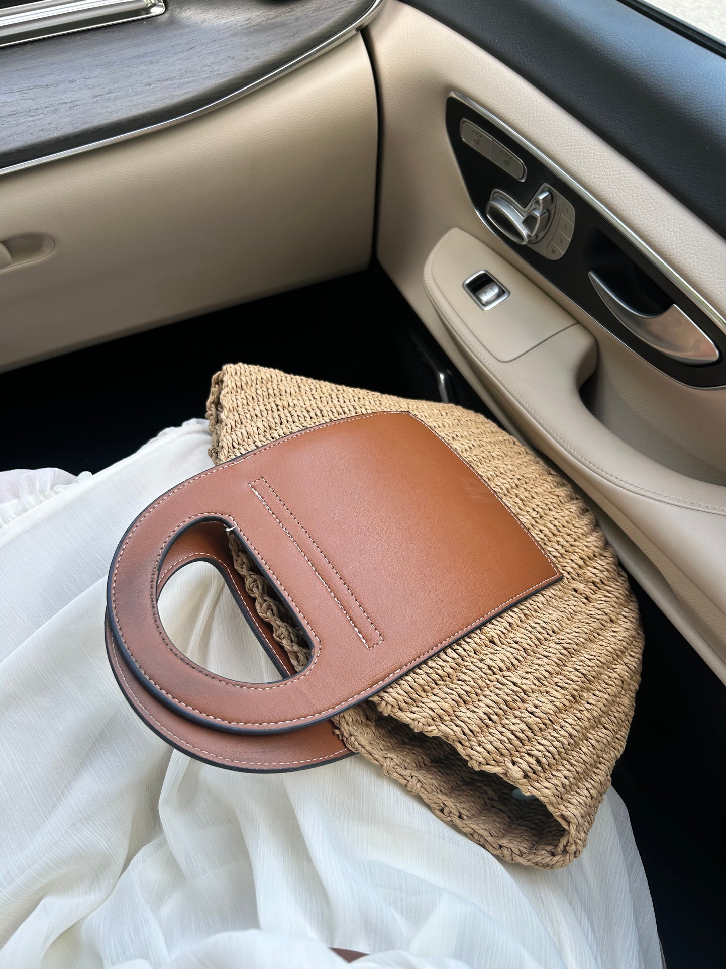 luxury summer straw tote bag for women placed in a car interior