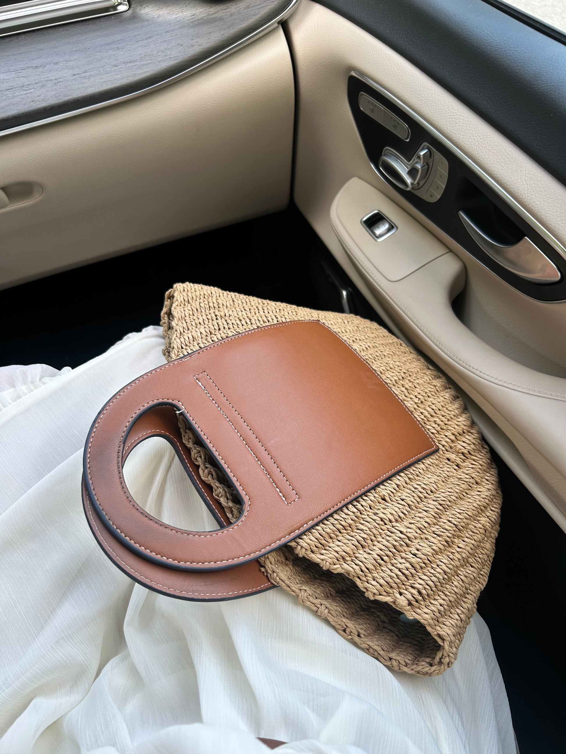 luxury summer straw tote bag for women placed in a car interior