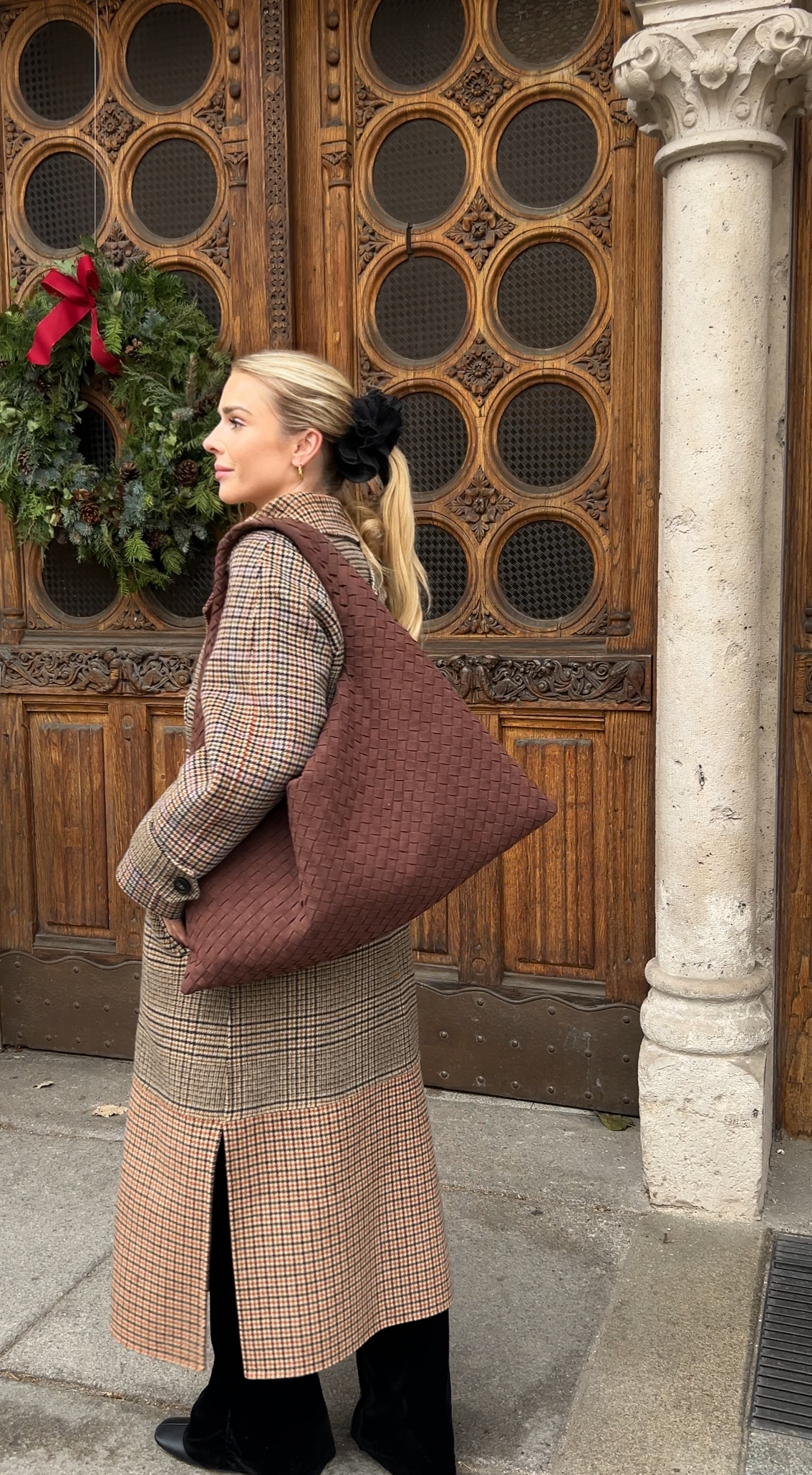 Christmas markets walk in Hungary Budapest wearing warm winter coat styled with large hobo shoulder bag from vegan leather woven design purse for women is ideal travel bag with large capacity and can be worn as a laptop work bag inspired by designer