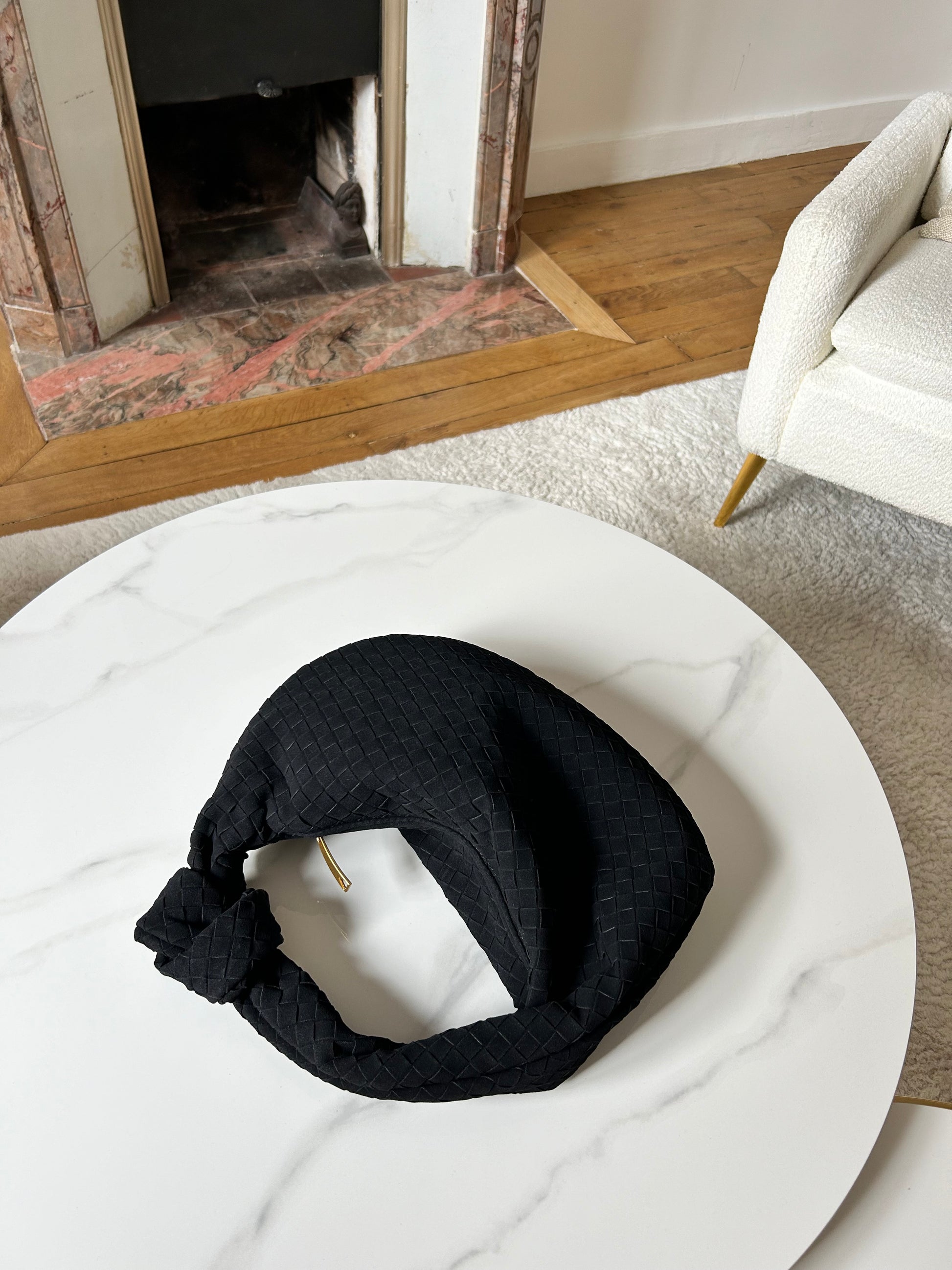 minimalist woven suede black handbag placed on a table