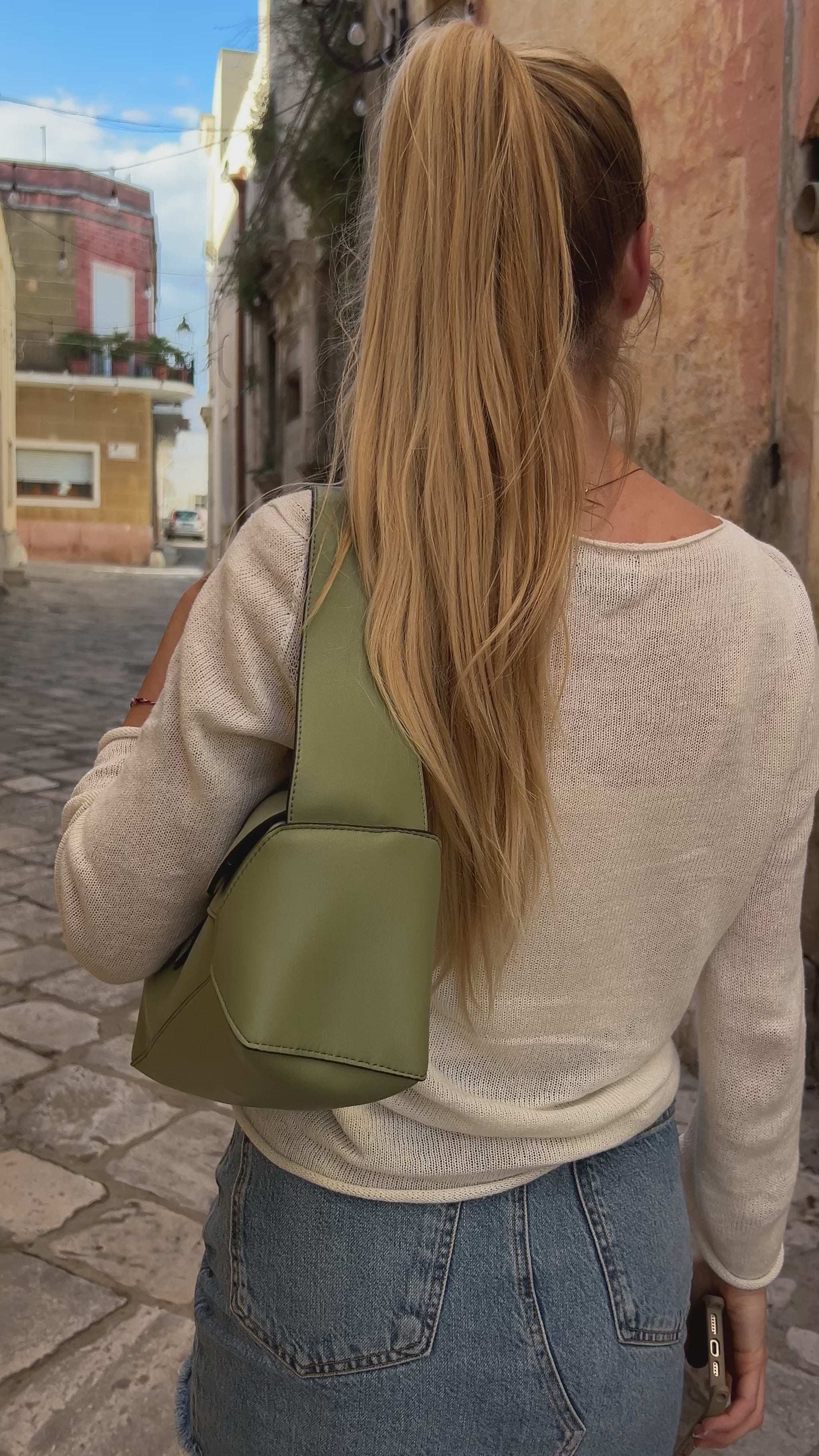 woman wearing a gree puzzle bag made from vegan leather in highest quality