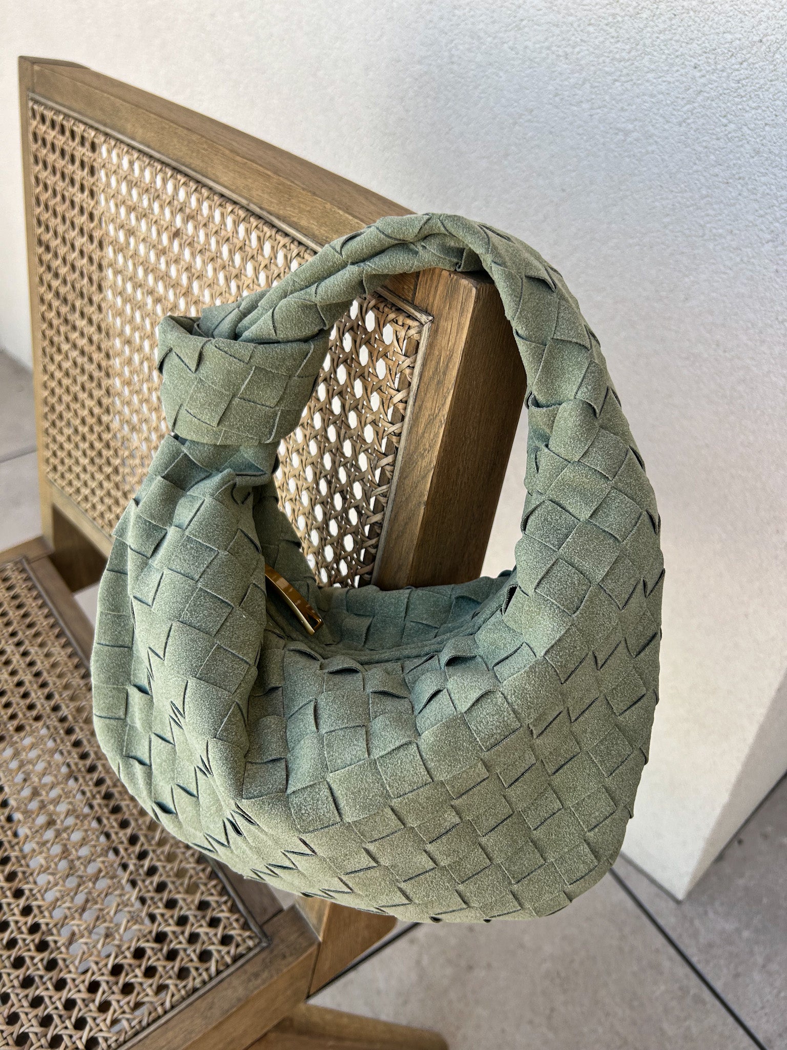small green woven clutch holding essentials phone keys