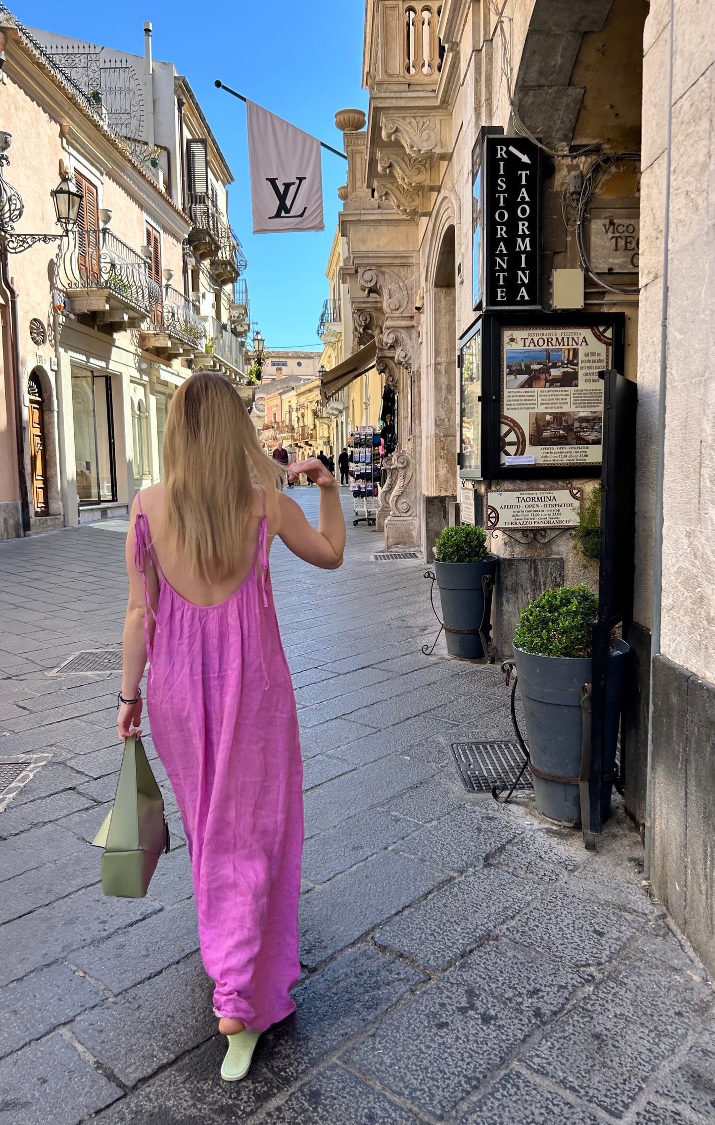 woman walking streets of Taormina in Sicily, wearing the luxury puzzle hobo bag in green colour
