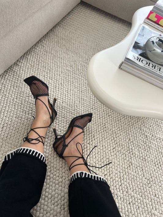 Black Mesh Lace-Up Heels
Turn heads wherever you go in our black lace-up mesh stiletto heels, the perfect fusion of elegance and bold femininity. These statement high heels feature a sexy see-through fishnet design, sleek ankle wrap straps, and a pointed open toe silhouette that instantly elongates the legs. Whether you're headed to a romantic dinner, a fashion-forward event, or a rooftop soirée, these heels elevate any outfit with confidence and glamour.