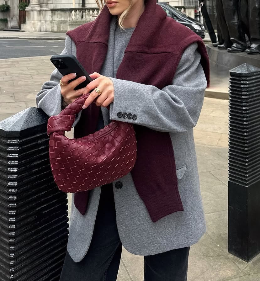 woman holding woven merlot clutch bag with oversized blazer minimalist luxury style