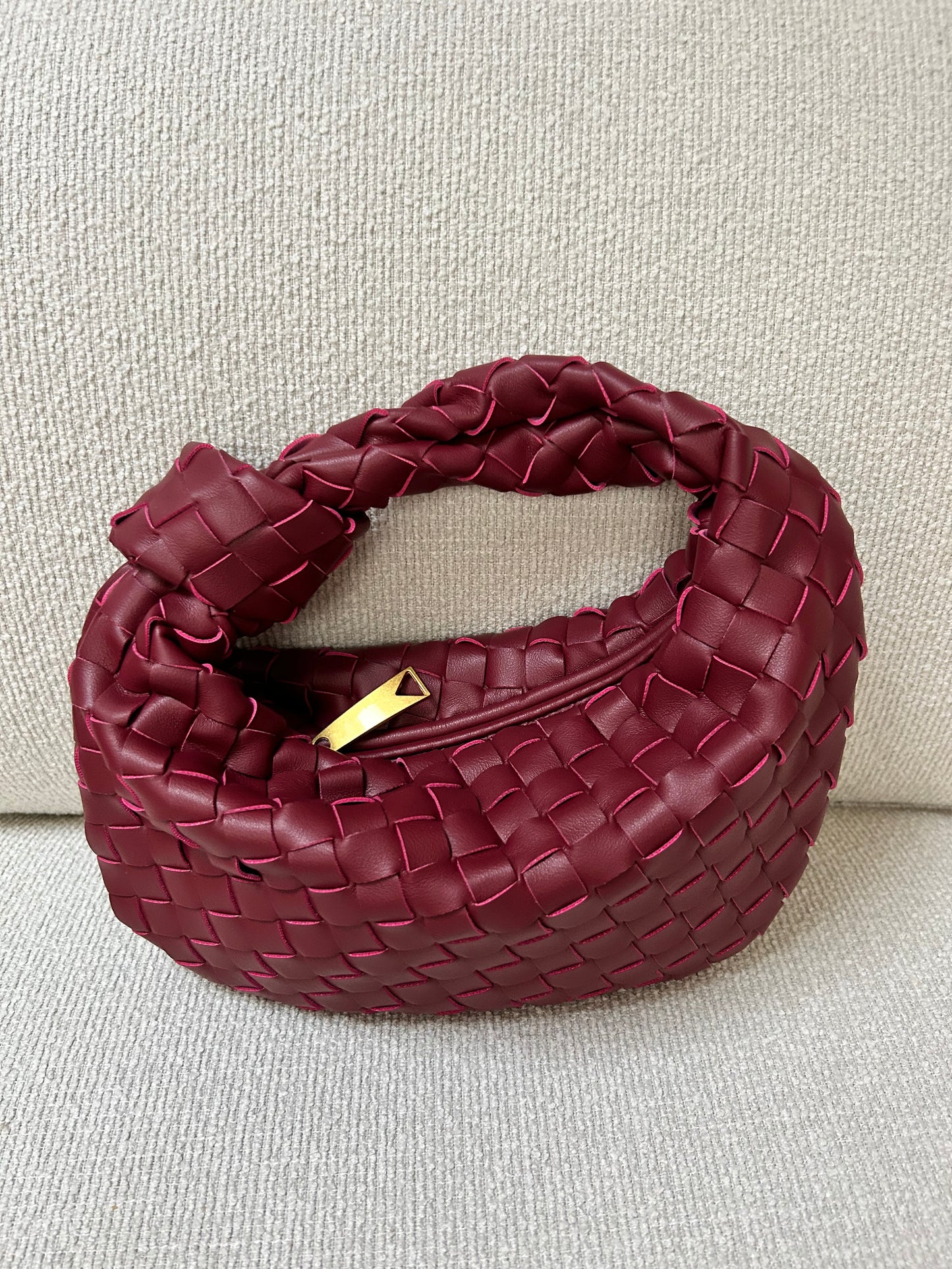 woven burgundy clutch bag with sculpted shape luxury vegan leather texture detail